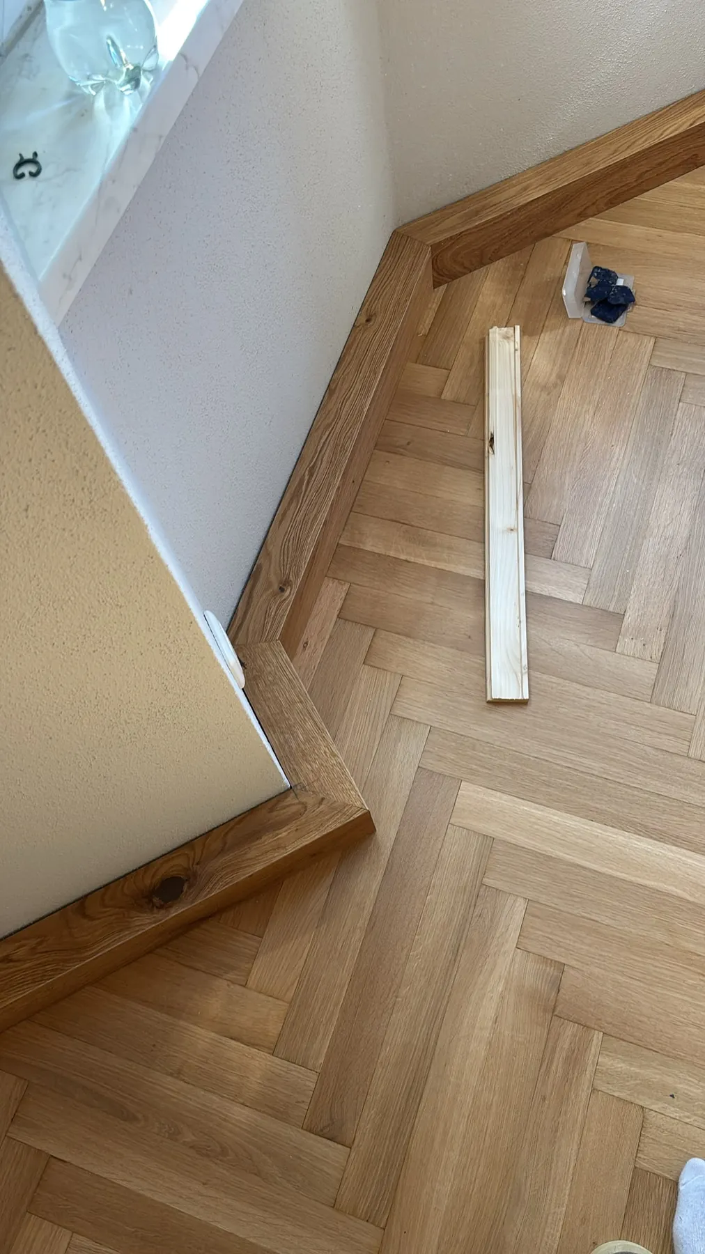 Fertige Abdeckleisten aus Eiche an einer Wandecke über dem Fischgrätparkett