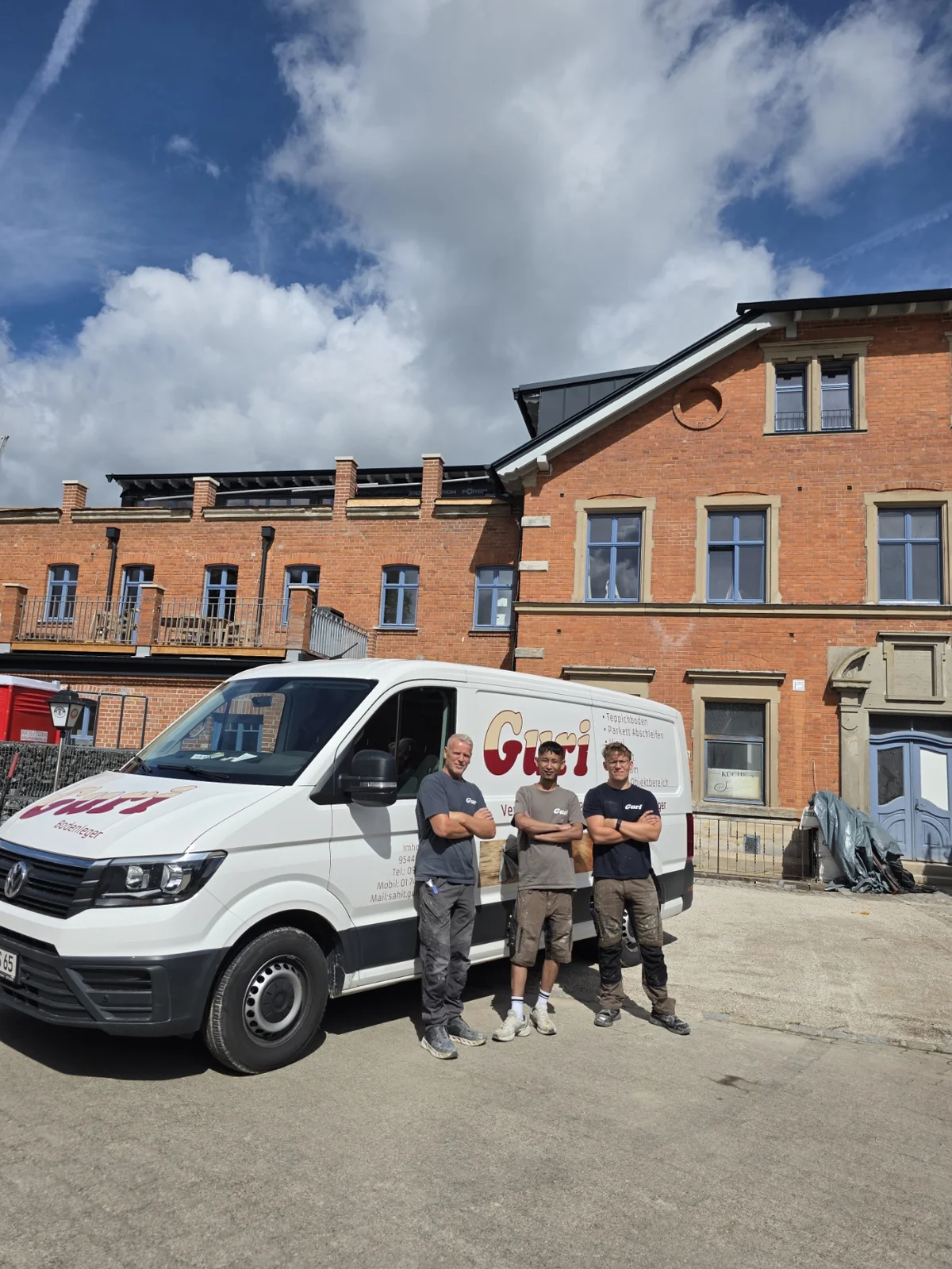Drei Personen in Guri-Arbeitskleidung vor dem Firmenfahrzeug von Guri Verlegeservice.